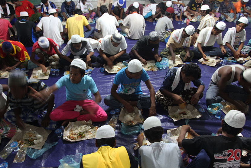 Puluhan imigran etnis Rohingya, Myanmar dan Bangladesh menyantap makanan di lokasi penampungan sementara, Pangkalan Susu, Langkat, Sumatera Utara, Minggu (17/5) malam.