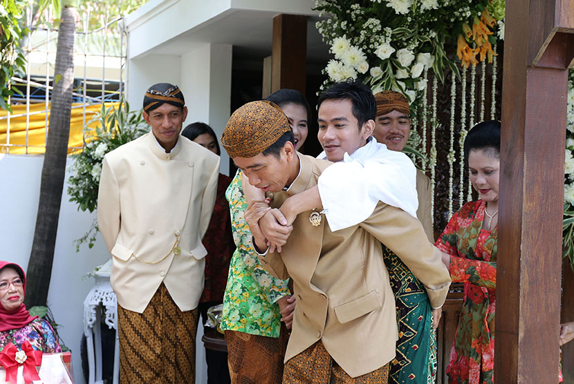   Presiden Joko Widodo (kiri) didampingi  Ibu Iriana Joko Widodo (kanan) menggendong  Gibran Rakabuming Raka (tiga kanan) saat prosesi siraman di  Solo, Jawa Tengah, Rabu (10/6).  (Antara/Maulana Surya)