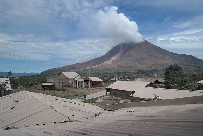  Warga melintas di Desa Namanteran yang tertutup debu vulkanik dengan latar belakang aktivitas Gunung Sinabung, Karo, Sumatera Utara, Selasa (16/6).   (Antara/Irsan Mulyadi)