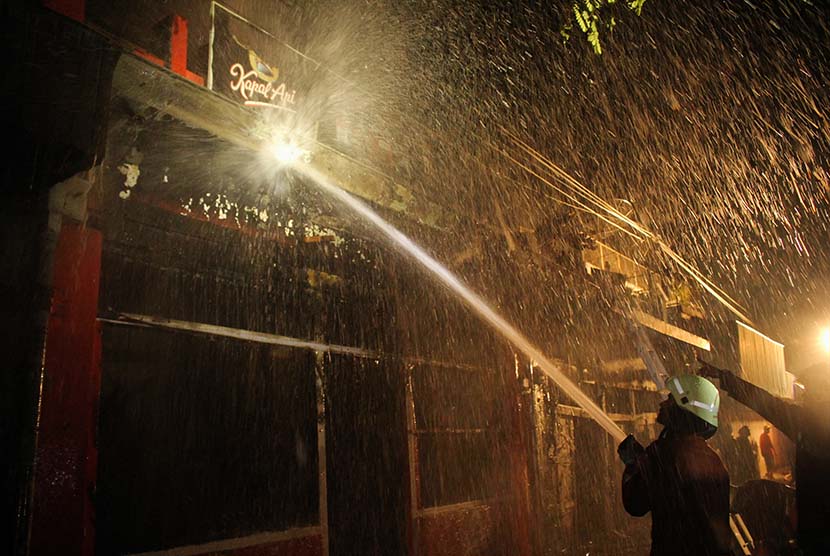  Petugas pemadam kebakaran melakukan proses pembasahan pada kebakaran Toko Aman Jaya di Keputran, Surabaya, Jawa Timur, Kamis (18/6).  (Antara/Didik Suhartono)