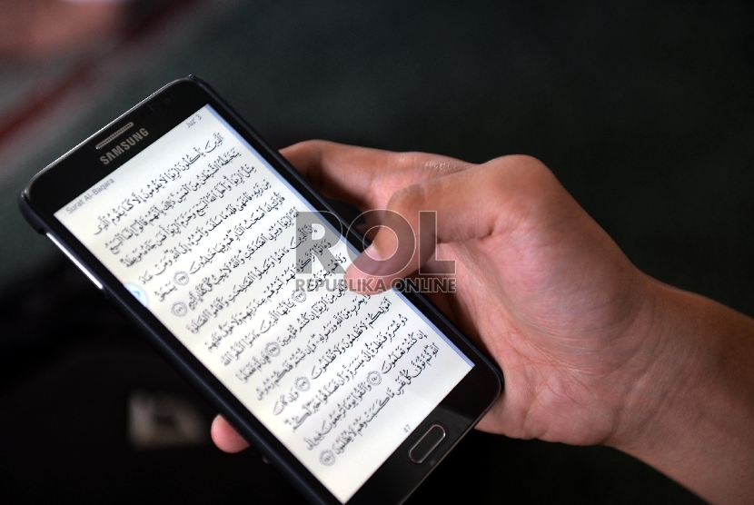 Seorang jamaah Masjid Agung Al-Azhar membaca ayat Alquran melalui ponsel usai menunaikan ibadah shalat Jumat, Jakarta Selatan, Jumat (19/6). (Republika/Rakhmawaty La'lang)