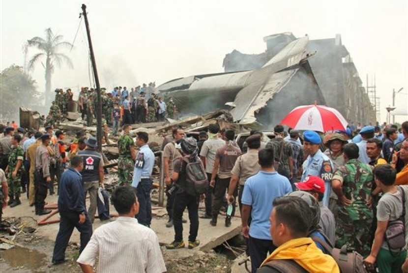  Petugas mengevakuasi reruntuhan pesawat Hercules C-130 yang jatuh di Jalan Jamin Ginting, Medan, Selasa (30/6).  (AP/Dedy Zulkifli)