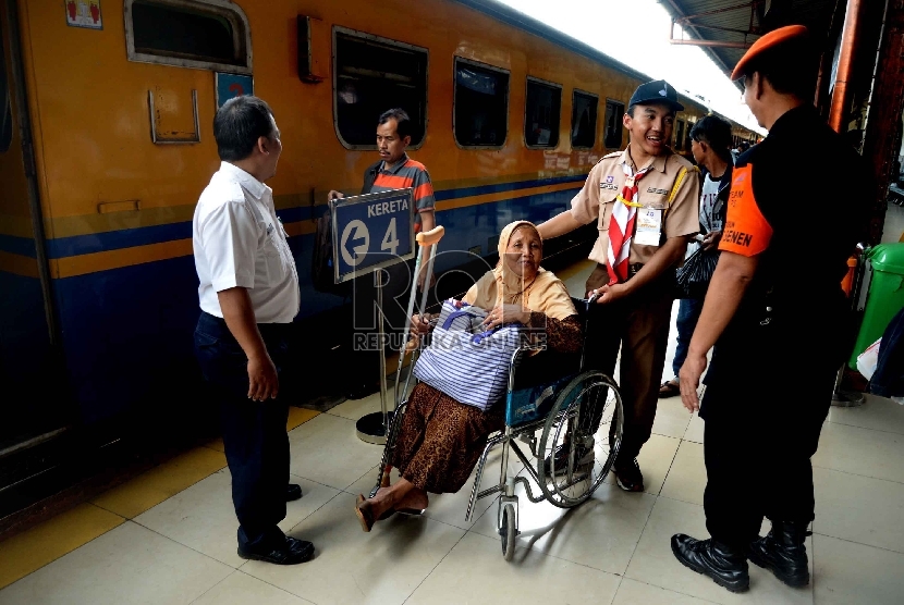 Anggota Praja Muda Karana (Pramuka) membantu penumpang di Stasiun Pasar Senen, Jakarta, Ahad (12/7).  (Republika/Yasin Habibi)