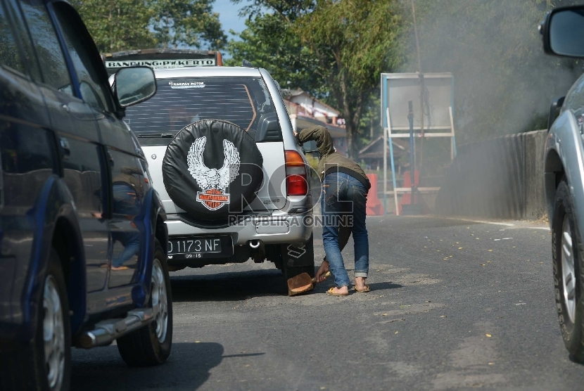 Pengganjal ban mengganjal kendaraan pemudik yang terjebak kemacetan di tanjakan kawasan Ciburial,Jawa Barat, Rabu (15/7).