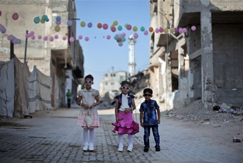  Tiga anak Palestina berfoto bersama saat merayakan Hari Raya Idul Fitri di Gaza, Palestina, Jumat (17/7).  (AP/Khalil Hamra)