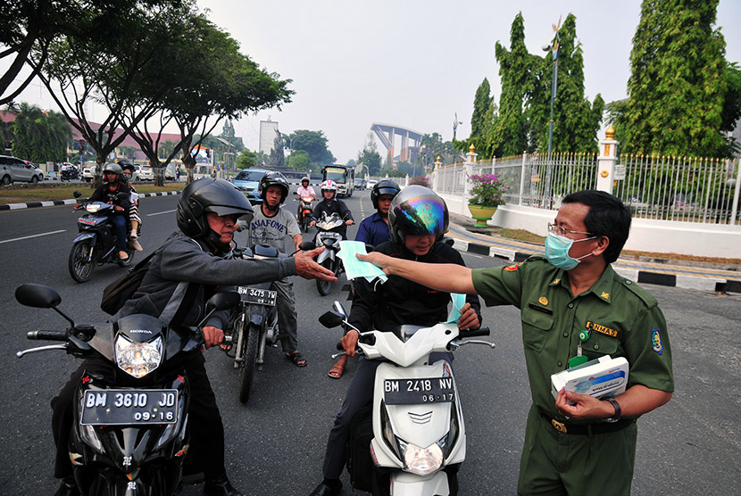 Sejumlah warga mengenakan masker medis yang dibagiakan Dinas Kesehatan Provinsi Riau saat kabut asap kebakaran menyelimuti Kota Pekanbaru, Senin (27/7).   (Antara/FB Anggoro)