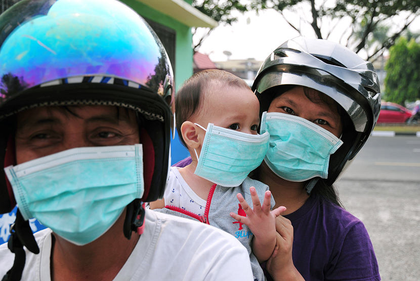    Sejumlah warga mengenakan masker medis yang dibagiakan Dinas Kesehatan Provinsi Riau saat kabut asap kebakaran menyelimuti Kota Pekanbaru, Senin (27/7).   (Antara/FB Anggoro)