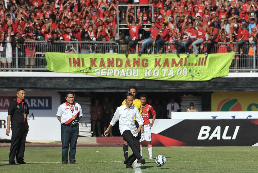 Presiden Joko Widodo (tengah) didampingi Ketua Penyelenggara Erick Thohir (kedua kiri) dan Gubernur Bali Made Mangku Pastika (kiri) menendang bola saat membuka pertandingan Piala Presiden di Stadion Dipta, Gianyar, Ahad (30/8). 