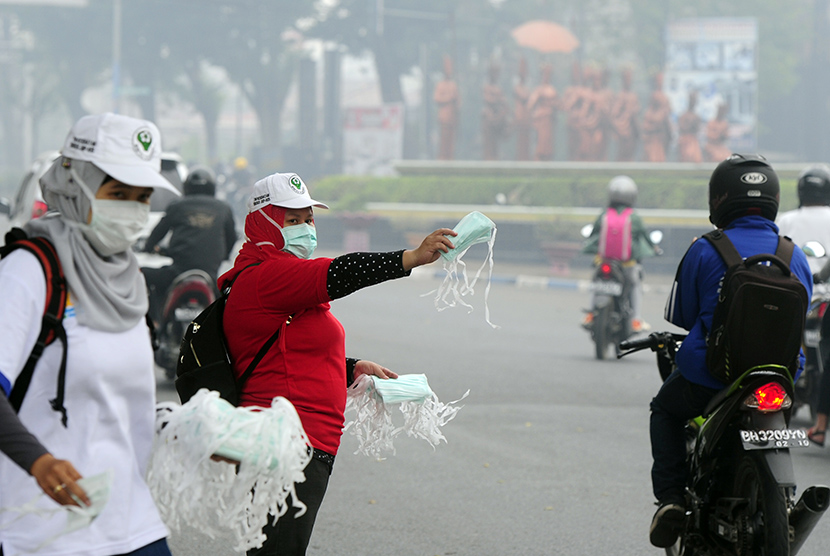   Seorang petugas membagikan masker gratis kepada pengendara yang melintasi di Jambi (ilustrasi)