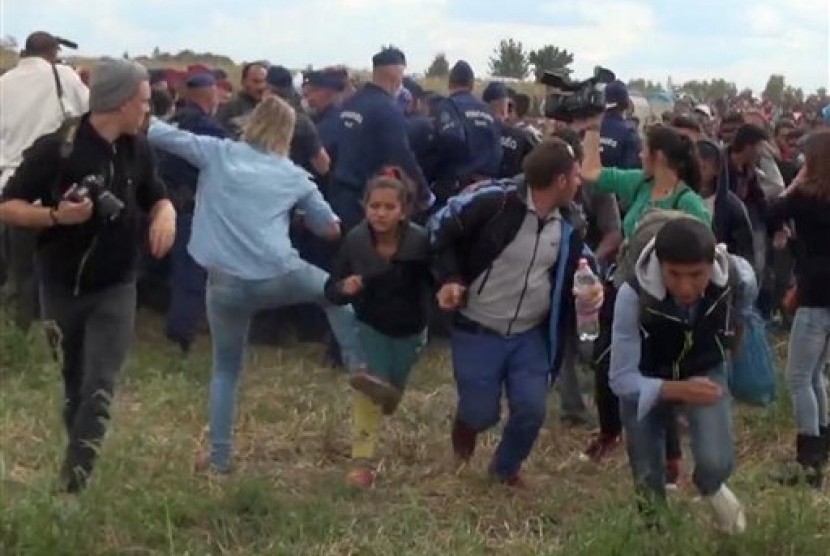  Pewarta video Petra Laszlo (kedua kiri) terekam kamera saat ia menendang seorang anak imigran yang berusaha melarikan diri di Desa Roszke, Hungaria, Rabu (9/9).  (AP)
