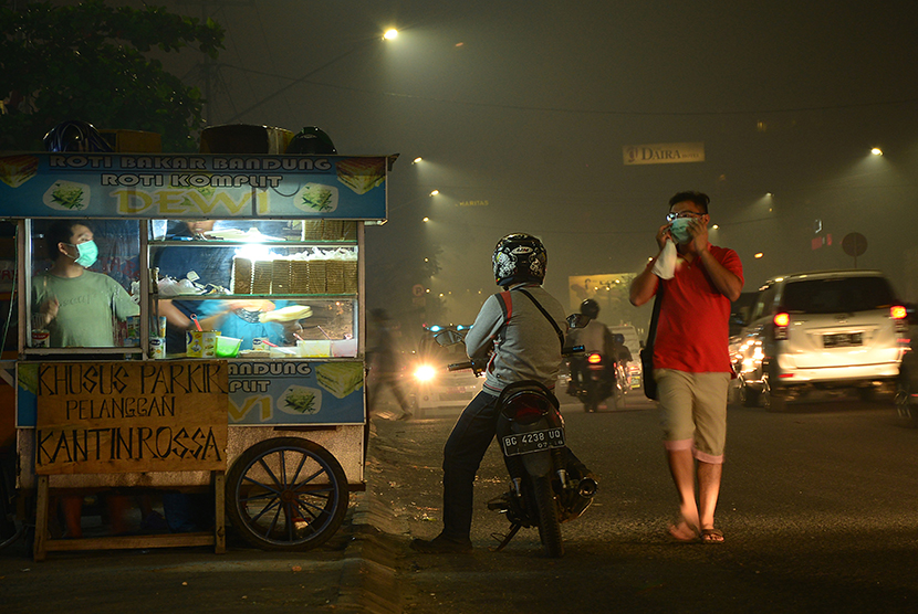  Pedagang dan pejalan kaki menggunakan masker saat beraktifitas malam karena kabut asap di jalan Sudirman Palembang, Sumatera Selatan, Rabu (9/9). (Antara/Yahanam Sulam)