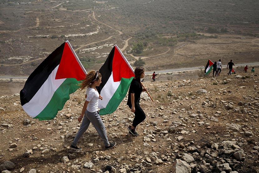 Dua anak membawa bendera Palestina.