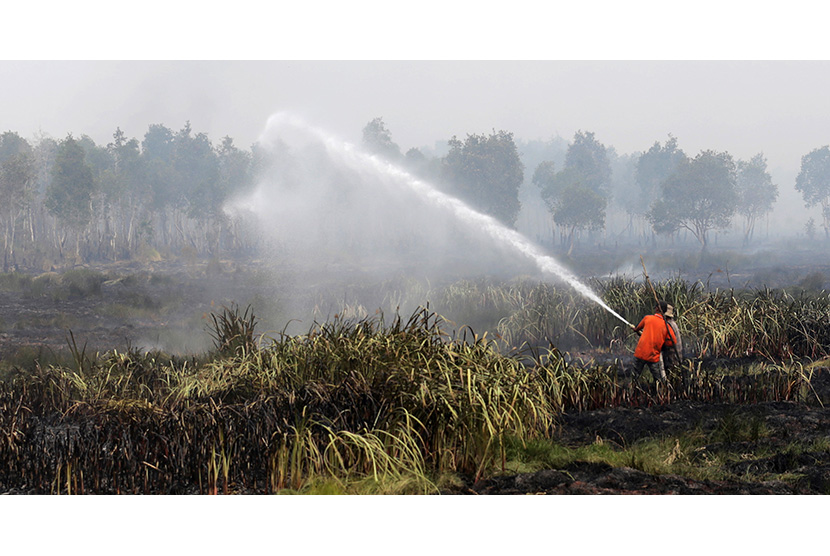  Petugas Badan Penanggulangan Bencana Daerah (BPBD) Kabupaten Ogan Ilir melakukan pemadaman kebakaran lahan gambut dari udara di Daerah Sei Rambutan, Ogan Ilir, Indralaya, Sumatera Selatan, Kamis (17/9).  (Antara/Nova Wahyudi)
