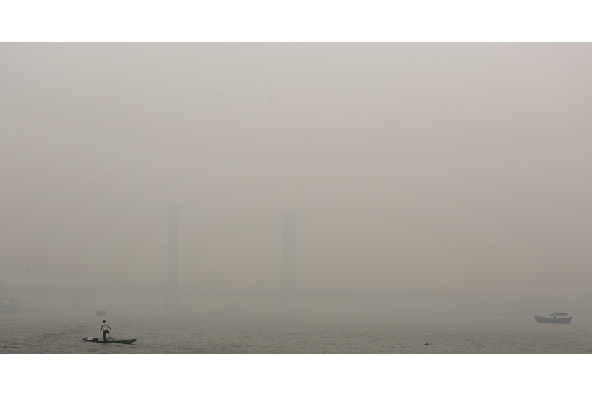  Nelayan mencari ikan diperairan sungai musi dengan latar jembatan Ampera yang tertutup kabut asap, Palembang, Sumsel. Selasa (29/9).   (Antara/Nova Wahyudi)