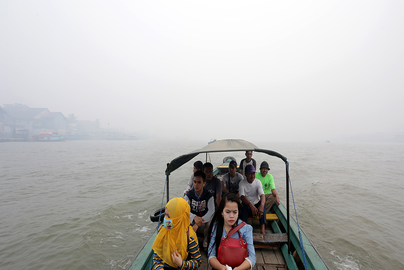   Sejumlah warga menyeberangi sungai Musi dengan menaiki kapal tradisional di perairan sungai musi yang tertutup kabut asap, Palembang, Sumsel. Selasa (29/9).   (Antara/Nova Wahyudi)