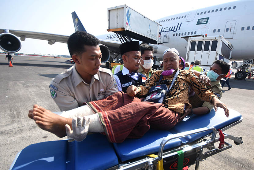Petugas medis mengangkat Murodi Yahya Kasani (55), jamaah haji kloter pertama embarkasi Surabaya asal Kabupaten Magetan ketika tiba di Bandar Udara Internasional Juanda Surabaya di Sidoarjo, Jawa Timur, Selasa (29/9).  (Antara/M Risyal Hidayat)