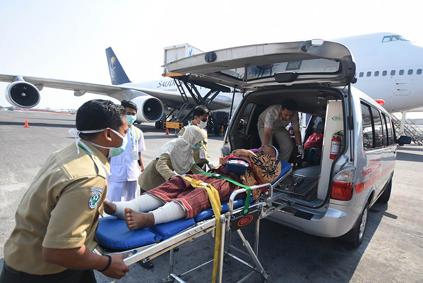 Petugas medis mengangkat Murodi Yahya Kasani (55), jamaah haji kloter pertama embarkasi Surabaya asal Kabupaten Magetan ketika tiba di Bandar Udara Internasional Juanda Surabaya di Sidoarjo, Jawa Timur, Selasa (29/9).  (Antara/M Risyal Hidayat)
