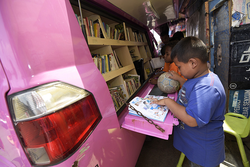 Sejumlah anak membaca buku yang disediakan gratis di mobil perpustakaan keliling, Tanah Abang, Jakarta Pusat, Ahad (11/10).   (Antara/Sigid Kurniawan)
