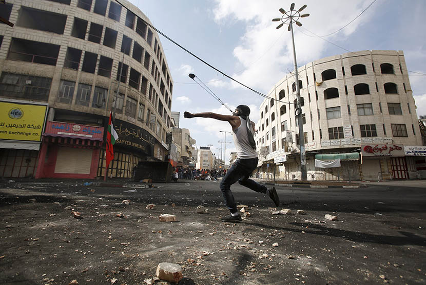   Pengunjuk Palestina bentrok dengan pasukan pendudukan Israel di Hebron, Palestina  Sabtu (10/10).  (REUTERS/Mussa Qawasma)