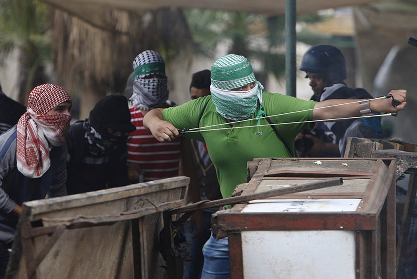   Pengunjuk Palestina bentrok dengan pasukan pendudukan Israel di Hebron, Palestina  Sabtu (10/10).  (REUTERS/Mussa Qawasma)