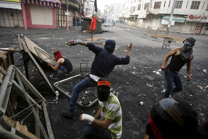   Pengunjuk Palestina bentrok dengan pasukan pendudukan Israel di Hebron, Palestina  Sabtu (10/10).  (REUTERS/Mussa Qawasma)