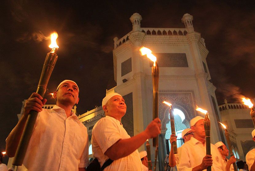   Umat Muslim memegang obor ketika mengikuti pawai dari Masjid Raya Al Mashun menuju Masjid Agung, Medan, Sumatera Utara, Selasa (13/10) malam.  (Antara/Irsan Mulyadi)