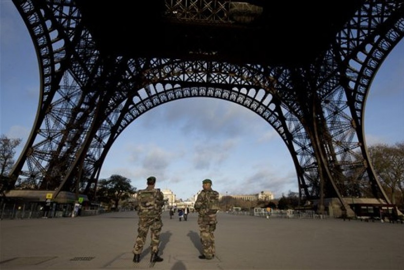 Tentara Prancis berpatroli di Menara Eiffel yang ditutup pada hari pertama berkabung nasional di Paris, Ahad (15/11).  (AP/Peter Dejong)