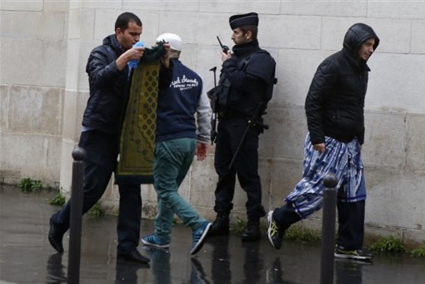  Sejumlah warga muslim melintasi polisi Prancis yang berjaga di luar masjid kota Paris, Jumat (20/11), usai shalat Jumat.  (AP/Francois Mori)