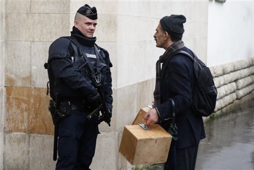  Seorang warga muslim melintasi polisi Prancis yang berjaga di luar masjid kota Paris, Jumat (20/11). (AP/Francois Mori)