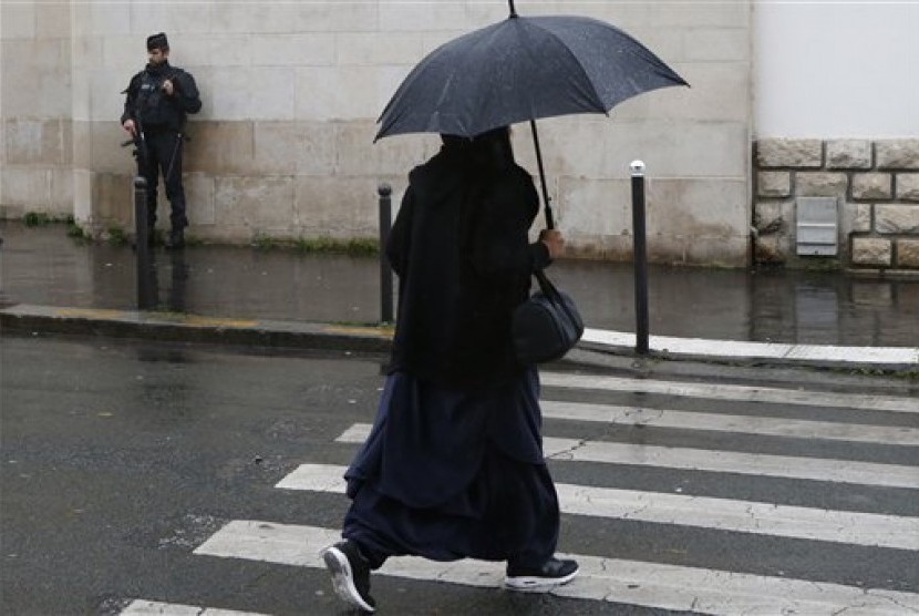 Kandidat Capres Prancis Minta Muslim Tinggalkan Ajaran Islam. Seorang wanita muslim melintasi polisi Prancis yang berjaga di luar masjid kota Paris, Jumat (20/11), usai shalat Jumat.  (AP/Francois Mori)
