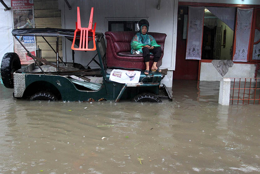 Sejumlah warga menonton televisi didalam rumahnya saat banjir yang melanda di daerah Keluarahan Pulai Anak Aia, Kecamatan Mandiangin Koto Selayang, Bukittinggi, Sumatera Barat, Jumat (27/11). (Antara//Muhammad Arif Pribadi)