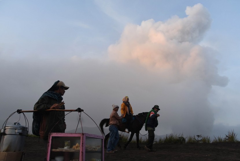 Sejumlah wisatawan beraktifitas dengan latar belakang abu vulkanik dari Gunung Bromo di Cemoro Lawang, Probolinggo, Jawa Timur, Ahad (6/12). (Antara/M Risyal Hidayat)