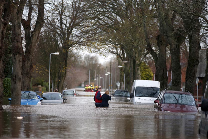 Warga melintasi genangan air banjir di kawasan pemukiman di Carlisle, Inggris (ilustrasi)