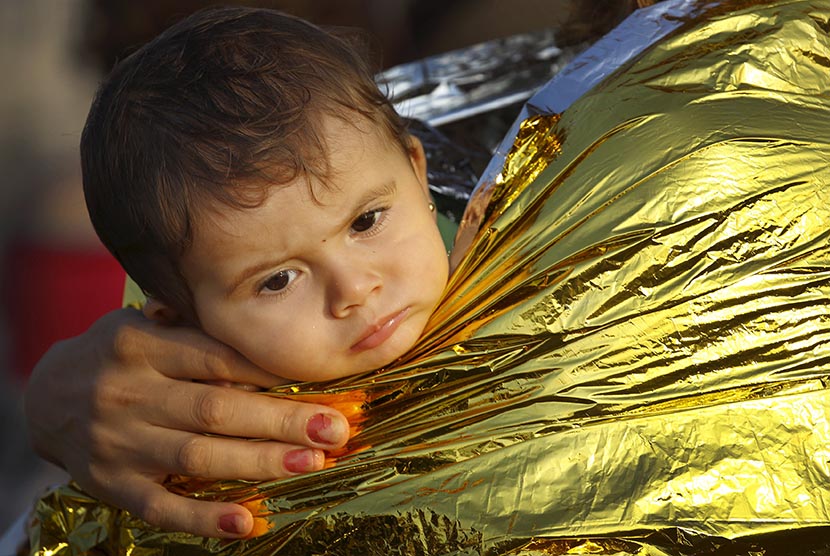  Seorang anak pengungsi Suriah diselimuti blanket thermal di Yunani.  (REUTERS/Yannis Behrakis)