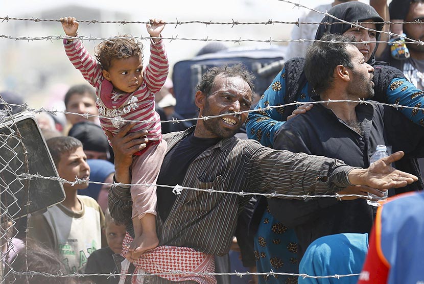  Pengungsi Suriah menanti untuk menyeberang ke Turki dibalik pagar kawat berduri.  (REUTERS/Umit Bektas)