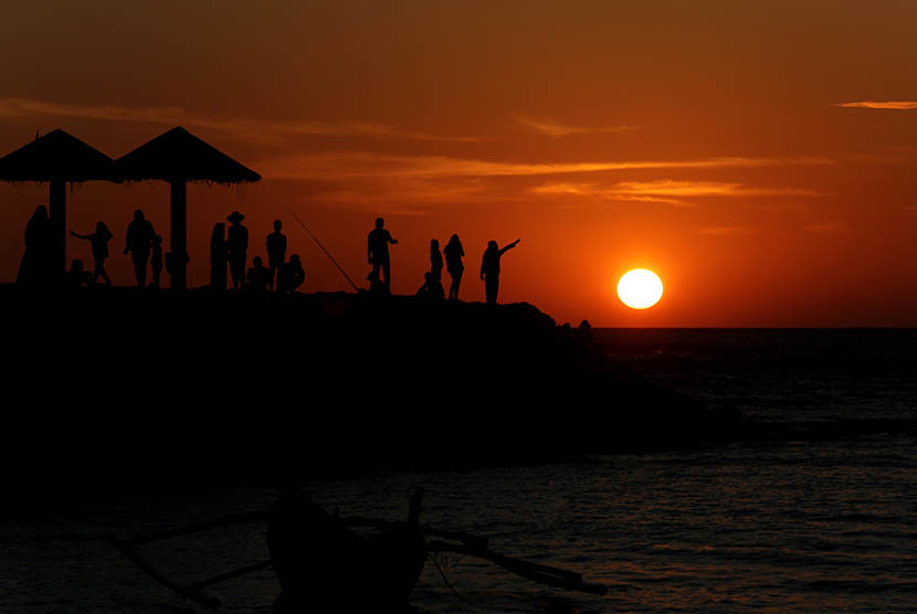 Warga menikmati matahari terbenam (sunset) pada hari akhir tahun 2015 di pantai Lampuuk, Kecamatan Lhoknga, Kabupaten Aceh Besar, Aceh, Kamis (31/12).  (Antara/Irwansyah Putra)