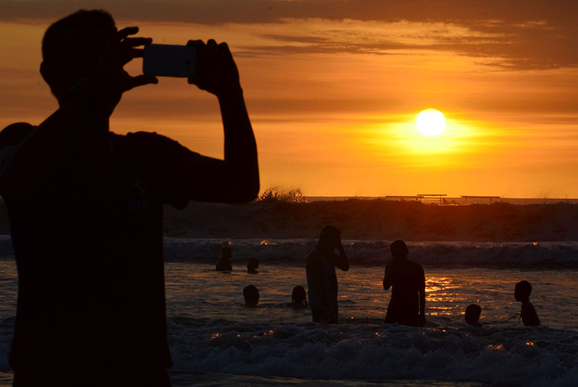 Wisatawan menyaksikan pemandangan matahari tenggelam (sunset) di Pantai Kuta, Badung, Bali, Kamis (31/12). (Antara/Fikri Yusuf)