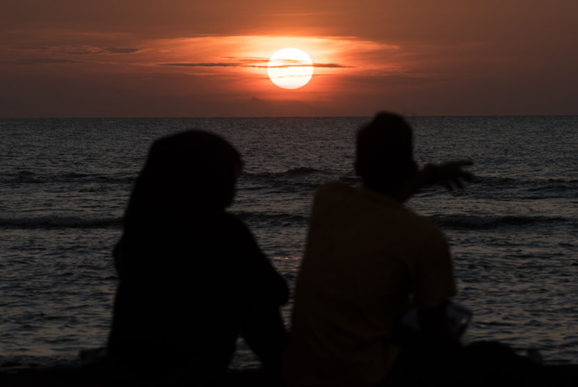Dua wisatawan menyaksikan matahari terbenam pada penghujung tahun 2015 di pelabuhan Paku, Anyer, Banten, Kamis (31/12). (Antara/M Agung Rajasa)