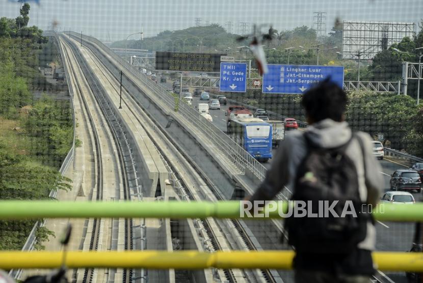 Warga melihat lintasan kereta LRT di kawasan Kampung Makassar, Jakarta, Kamis (3/10).