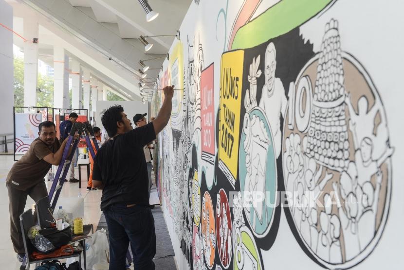 Seorang seniman saat membuat mural pada pameran Pekan Kebudayaan Nasional 2019 di Istora Senayan, Jakarta, Selasa (8/10).