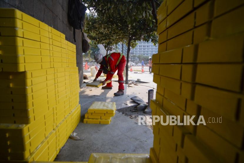 Pekerja menyelesaikan pemasang guiding block atau ubin pengarah bagi penyandang disabilitas di trotoar Bundaran HI, Jakarta, Jumat (11/10/2019).