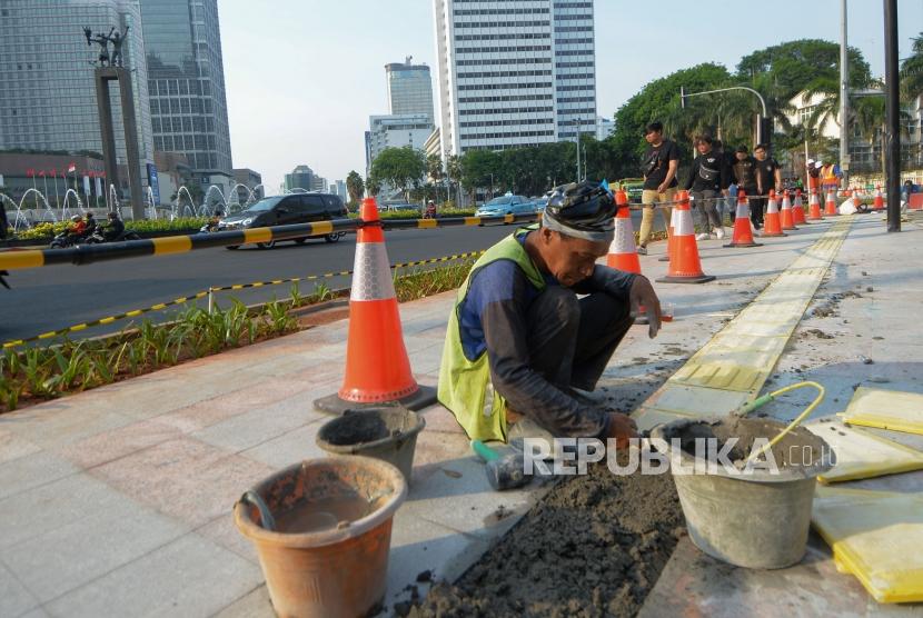 Pekerja menyelesaikan pemasang guiding block atau ubin pengarah bagi penyandang disabilitas di trotoar Bundaran HI, Jakarta, Jumat (11/10/2019).