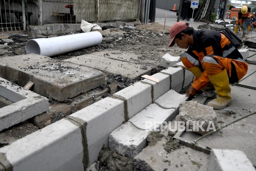 Pekerja menyelesaikan proyek revitalisasi trotoar di Jalan Kramat Raya, Jakarta Pusat, Senin (7/10/2019).