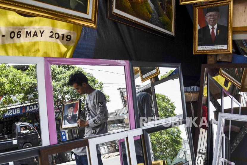 Pedagang merapikan poster Presiden Joko Widodo dan Wakil Presiden terpilih Ma'ruf Amin di salah satu kios figura di Kawasan Cicadas, Kota Bandung, Kamis (17/10).