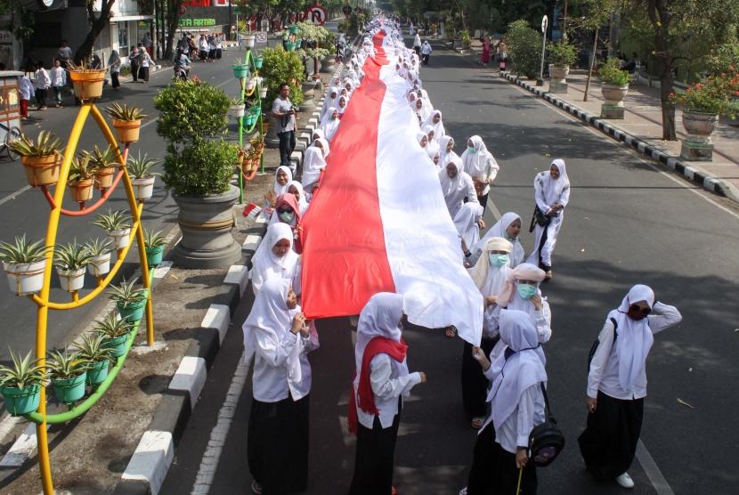 Santri membawa bendera merah putih sepanjang 1.000 meter saat pawai peringatan Hari Santri Nasional di Sidoarjo, Jawa Timur, Ahad (20/10/2019).