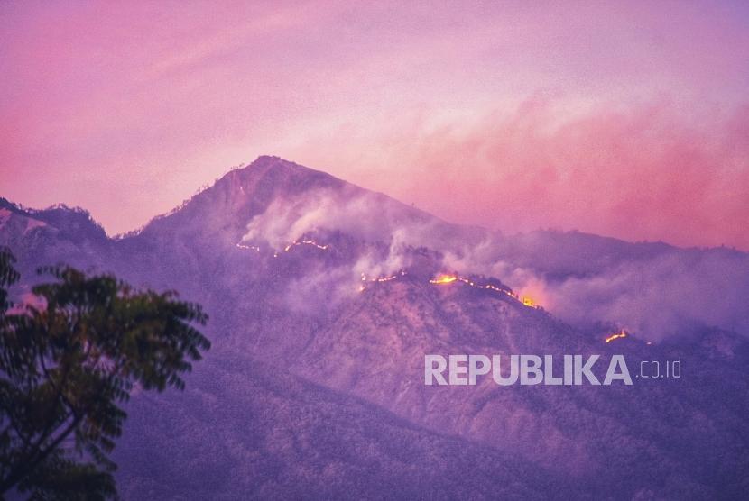 Kebakaran kawasan hutan pelawangan Senaru Gunung Rinjani terlihat menjelang matahari terbit dari Desa Anyar, Kecamatan Bayan, Lombok Utara, NTB, Ahad (20/10/2019).