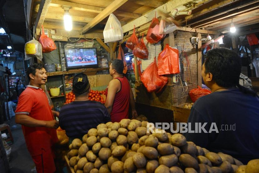 Pedagang sayuran menyaksikan acara pelantikan Presiden dan Wakil Presiden di Pasar Senen, Jakarta, Ahad (20/10/2019).