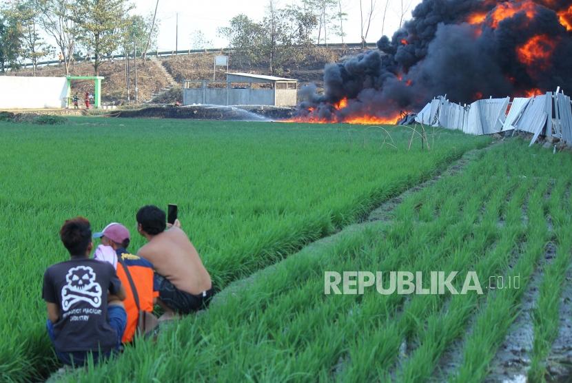 Penduduk mengabadikan kebakaran pipa Pertamina dilokasi proyek pembangunan Kereta Cepat Indonesia-Cina (KCIC), di Kampung Mancong, Kelurahan Melong, Kecamatan Cimahi Selatan, Kota Cimahi, Selasa (22/10).