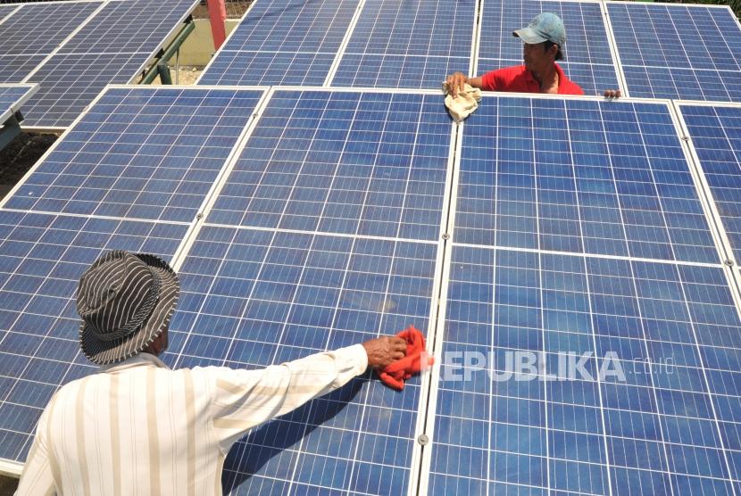 Pembangkit Listrik Tenaga Hybrid Warga membersihkan panel surya di Energi Mandiri Tenaga Surya dan Angin ( E Mas Bayu), Kampug Laut, Cilacap, Jawa Tengah, Kamis (24/10).