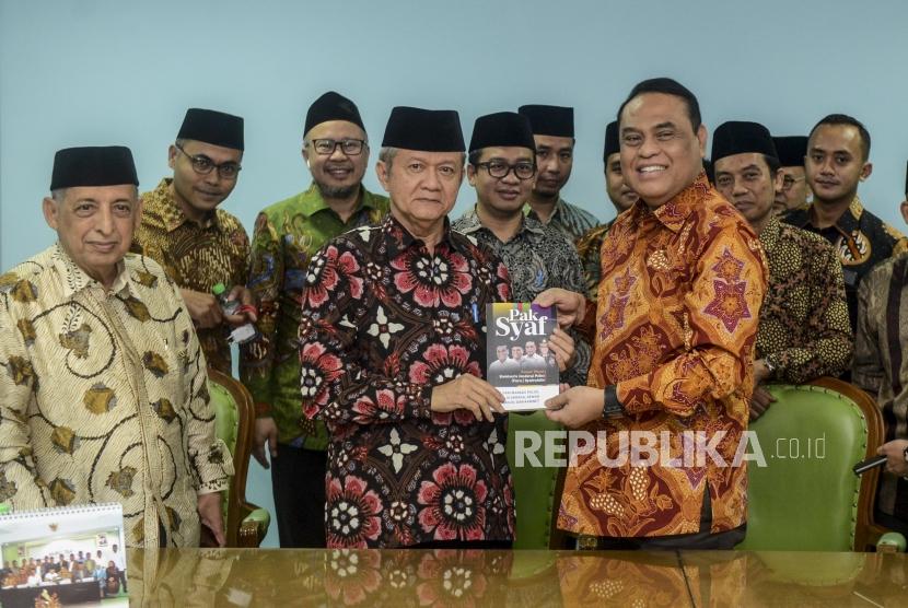 Wakil Ketua Dewan Masjid Indonesia Syafruddin (kanan depan) memberikan buku cinderamata kepada Sekjen MUI Anwar Abbas disaksikan Pemimpin Redaksi Republika Irfan Junaedi (kedua kiri) usai kunjungan ke Kantor MUI, Jakarta, Jumat (1/11).